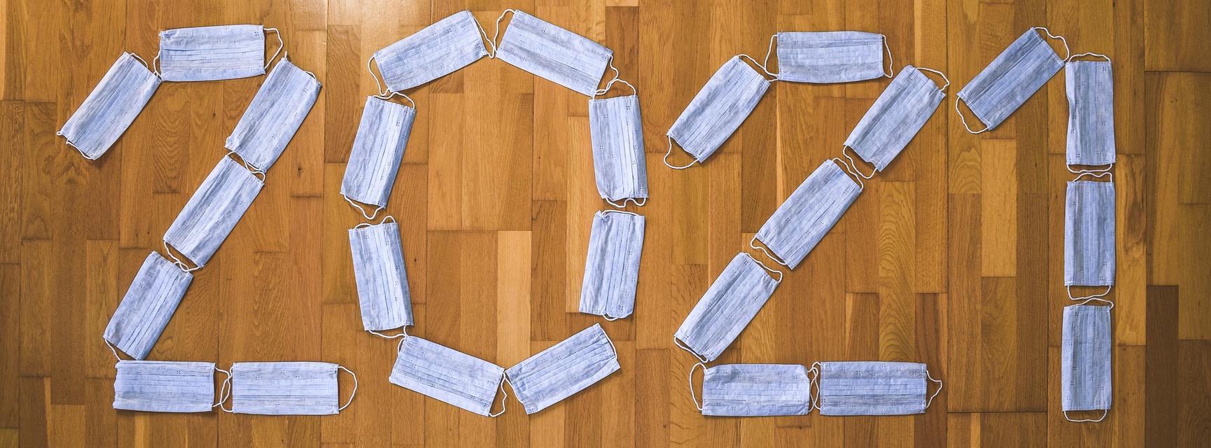 2021 spelt out with blue face masks on a wooden floor